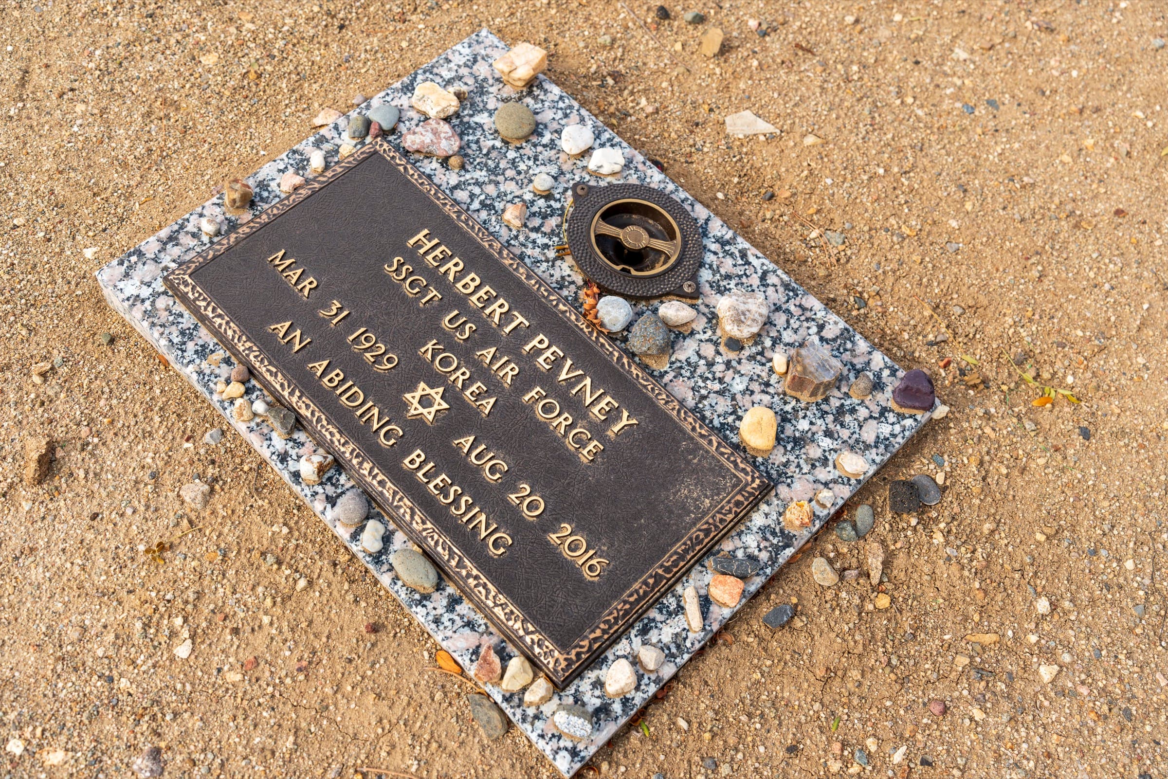 A veteran's bronze memorial marker with an American flag